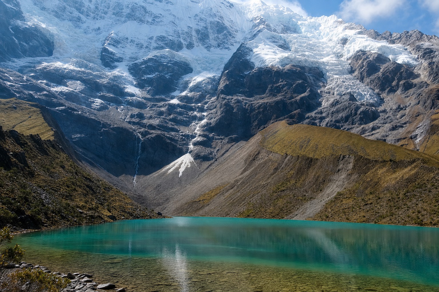 Turquoise water of Humantay Lake below the glacier face in late morning light
