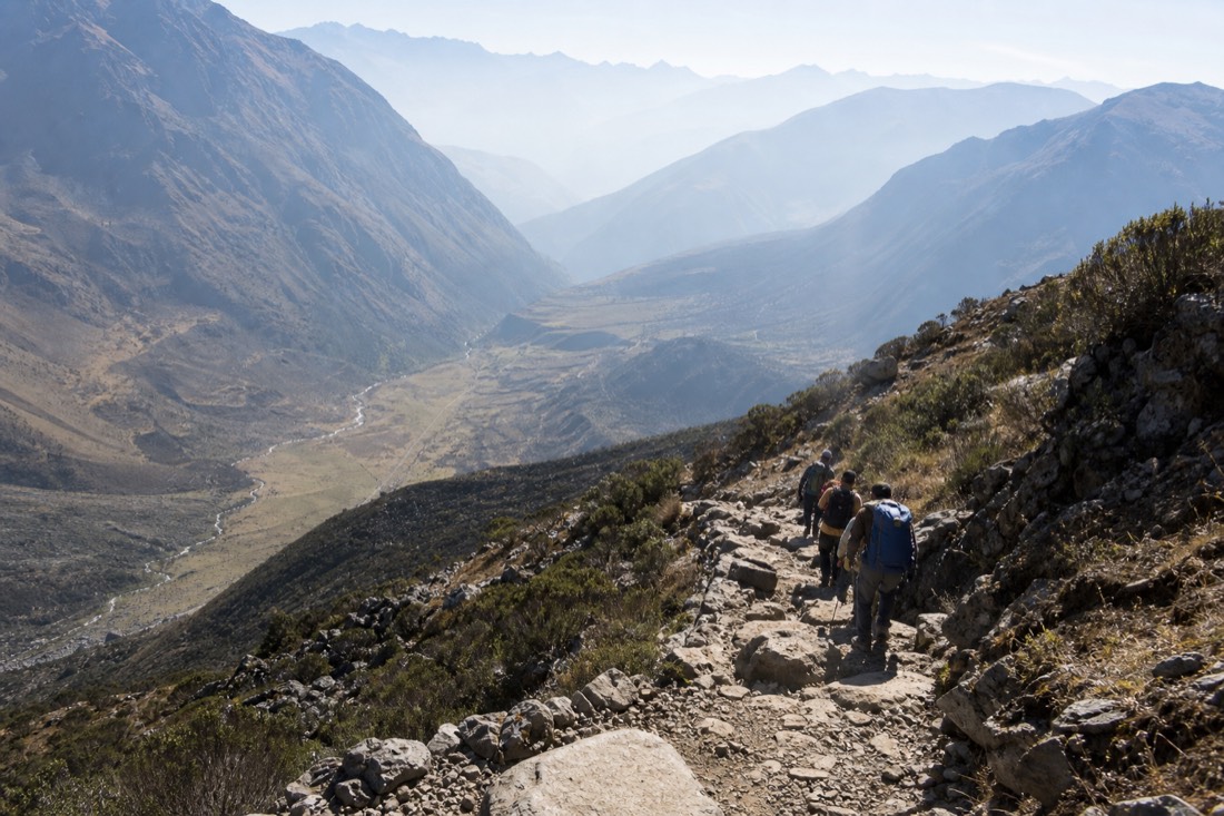 Hikers climbing the rocky switchback section of the Humantay trail above the Soraypampa valley