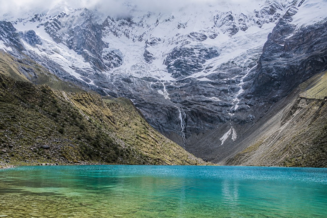 Humantay Lake showing gradient of turquoise water with the glacier wall and moraine behind